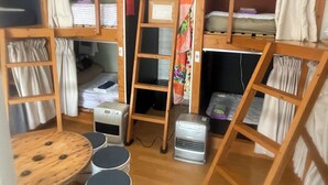 Un dormitorio con literas, una escalera, un calentador, una mesita y una silla.