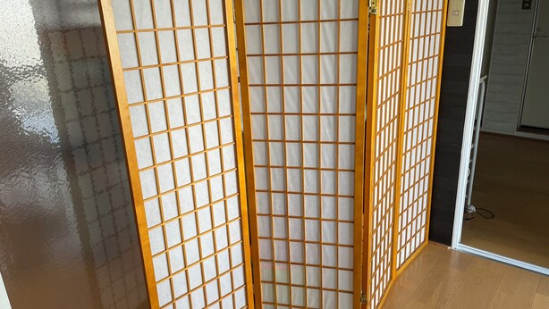 Una habitación con puerta corredera de fusuma, suelo de madera y una toma de corriente visible.
