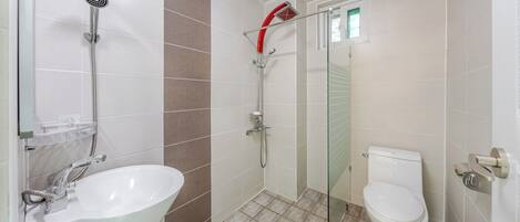 A bathroom with a white sink, a shower with a red head, and a toilet.