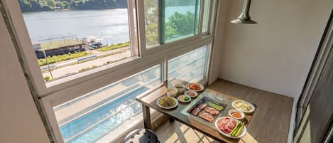 A balcony with a table set for a meal, a pool, and a view of a lake and mountains.