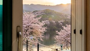 A scenic view through a window with cherry blossoms and a lake. - Gapyeong Eos Pension (Gapyeong)