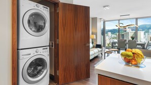 Un apartament modern amb rentadora, una porta de fusta, un sofà, zona de menjador i vista a la ciutat.