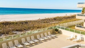 Blick auf ein Schwimmbecken mit Strand und Meer im Hintergrund.