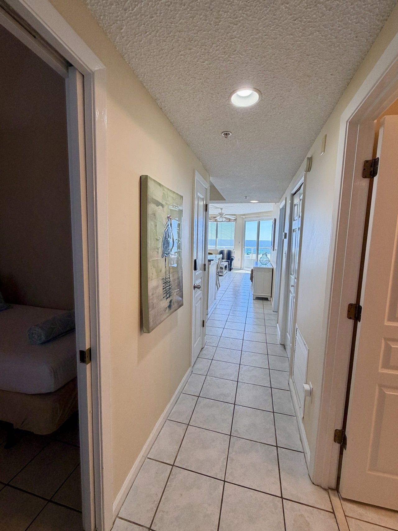 A corridor with a tiled floor, a ceiling light, and a door on the right.