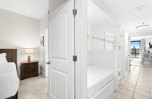 Ein Hotelzimmer mit Bett, Nachttisch, Lampe, Kleiderschrank und Blick ins Freie.