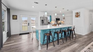 Een moderne keuken met een groot eiland, barstoelen en hanglampen.