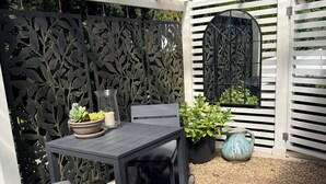 Een terras met een tafel en stoelen, omringd door een sierhekwerk en een potplant.
