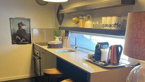 Een moderne keuken met een centraal eiland, barstoelen, hanglampen en een koffieapparaat.