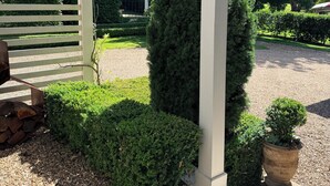 Een tuin met een pergola, strakke heggen en een grindpad.