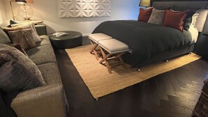 Een moderne slaapkamer met een bed, een bank, een tafeltje en een wandlamp.