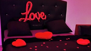 Un dormitorio con cama, almohadas y un letrero de neón.