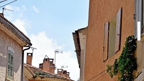 Una calle estrecha con edificios de arquitectura tradicional, que incluyen chimeneas y ventanas con contraventanas.