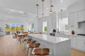 Una cocina moderna con armarios blancos, una isla grande e iluminación colgante.