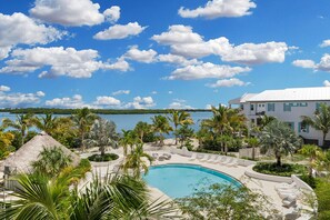 Una piscina rodeada de palmeras y un edificio blanco con vistas a un lago.