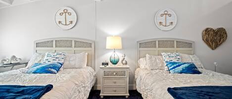 A double bed with a dark blue blanket, a bedside table with a lamp, and two decorative pillows.