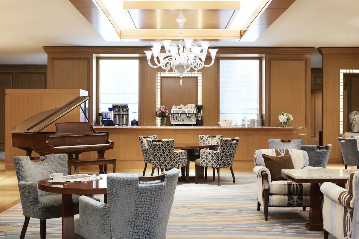 A grand piano, a bar area with a mirror, and a seating arrangement with patterned chairs and a table.
