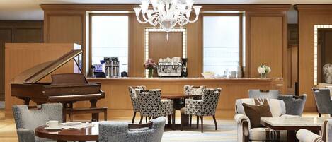 A grand piano, a bar area with a mirror, and a seating arrangement with patterned chairs and a table.