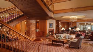 A grand lobby with a wooden staircase, a fireplace, plush seating, and a chandelier. - Charming Room w/ Pool Access, Ideal for University of Utah Visitors (Salt Lake City)