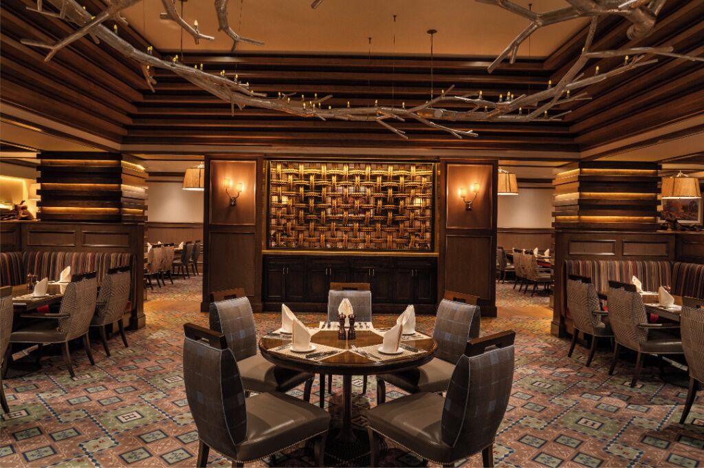 Un restaurant doté d’une grande table ronde au centre, de plusieurs espaces aménagés pour s’asseoir et d’un tapis à motifs.