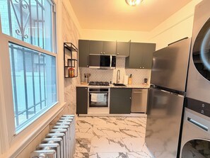 A compact kitchen with dark cabinets, a stainless steel refrigerator, a microwave, and a gas stove.