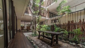 Um deck de madeira com um banco, cercado por pedras e plantas, que leva a uma porta de vidro.
