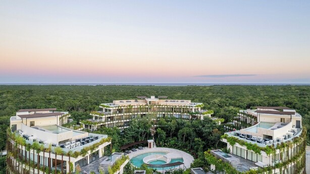 Et resort med flere bygninger, en central pool og en omgivende skov.