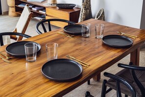 A wooden dining table with black plates, clear glasses, and gold chopsticks. - Selvatico PH and private pool by BT Homes (Tulum)