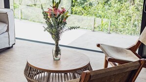 A modern dining area with a round table, wicker chairs, and a vase with flowers. - Selvatico PH and private pool by BT Homes (Tulum)