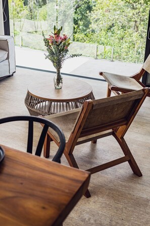 A modern dining area with a round table, wicker chairs, and a vase with flowers. - Selvatico PH and private pool by BT Homes (Tulum)