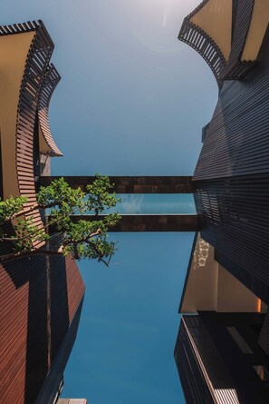 A modern building with a reflective pool and a tree in the foreground. - BT Homes - Stylish apartment near the sea (Tulum)