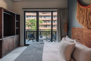 A bedroom with a bed, a TV, a balcony with a view of buildings, and a patterned rug. - BT Homes - Stylish apartment near the sea (Tulum)