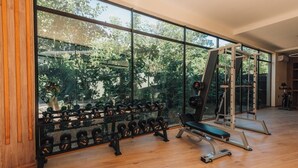 Un gimnàs amb grans finestres, sòl de fusta i diversos aparells d'exercici.