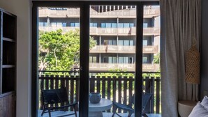 Un balcó amb vista a un edifici d'àmples proporcions, una taula rodona petita, dues cadires i un objecte decoratiu penjant.