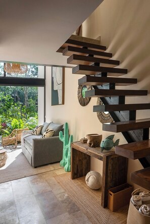 A modern interior with a spiral staircase, a grey sofa, and a view of greenery outside. - 20%OFF Loft in excellent location brand new (Tulum)