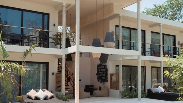 Een modern huis met twee verdiepingen, een zwembad, zitplaatsen buiten en een trap.