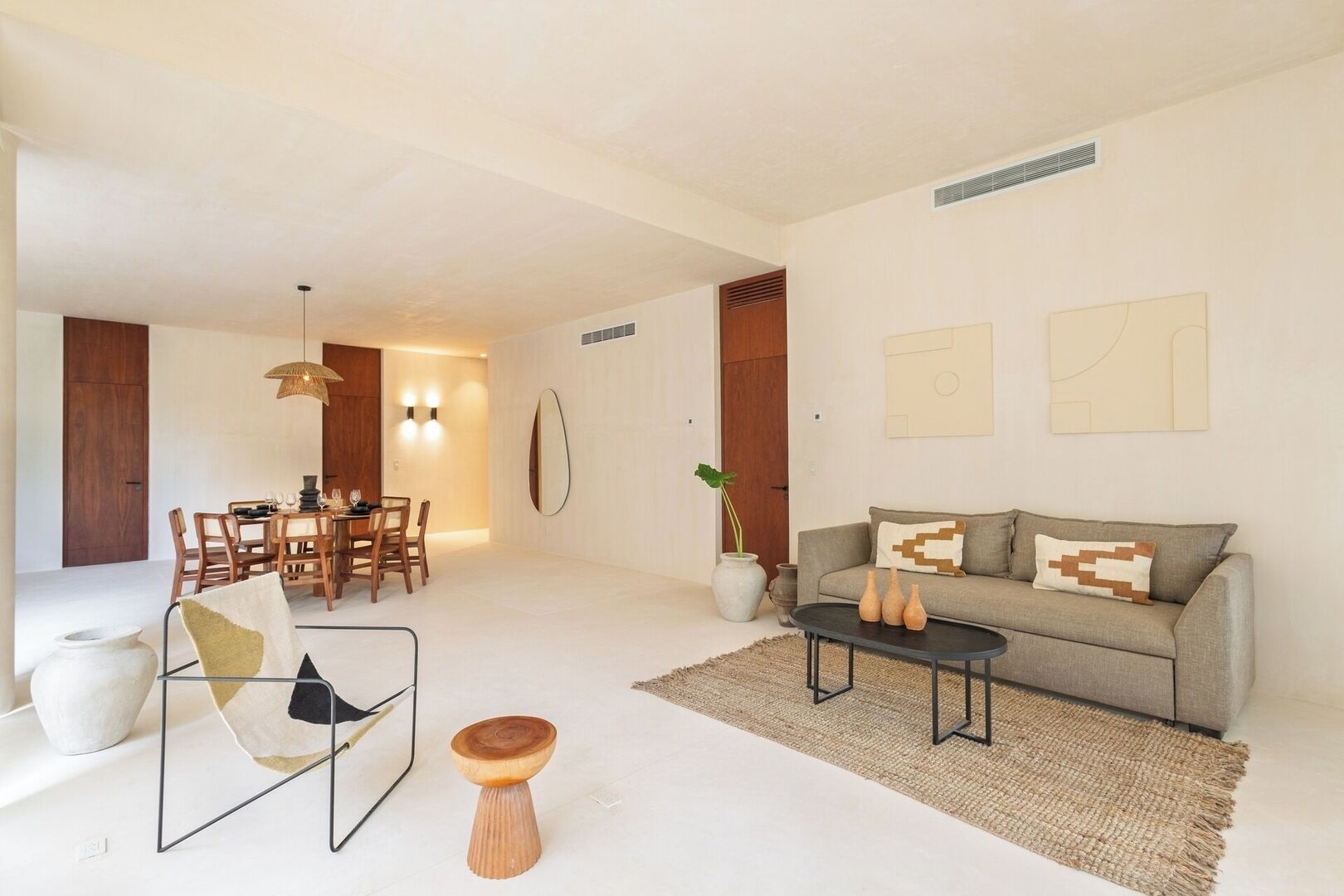 A modern living room with a sofa, coffee table, and dining area with chairs and a table.