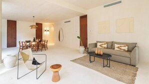 Un saló modern amb sofà, taula de centre i zona de dinar amb cadirees i taula.