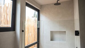 Une salle de bain moderne dotée d’une douche à parois de verre, d’une fenêtre et d’un luminaire encastré au plafond.