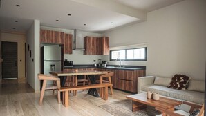 Une cuisine moderne avec des meubles en bois, un coin repas comprenant une table et des chaises en bois, un canapé et une table basse.