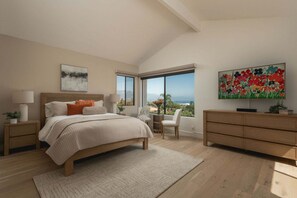 A bedroom with a bed, bedside tables, a desk, a chair, a dresser, and a large window with a view. - Designer Mesa Escape with Stunning Ocean Views (Santa Barbara)