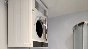A compact laundry area with a wall-mounted dryer and a front-loading washing machine.