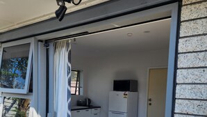 A kitchen with a microwave, refrigerator, and a window with curtains.