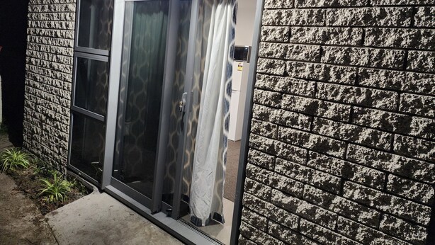 A building with a stone facade, a sliding glass door, and a vent on the wall.