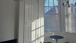 A room with a white door, a small round table, and two chairs. There are two chandeliers hanging from the ceiling. - Apartment Sleeps 2 with Parking & Garden (Greater London)