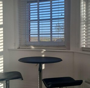 Ein Zimmer mit Fenster, einem runden Tisch und zwei Stühlen.