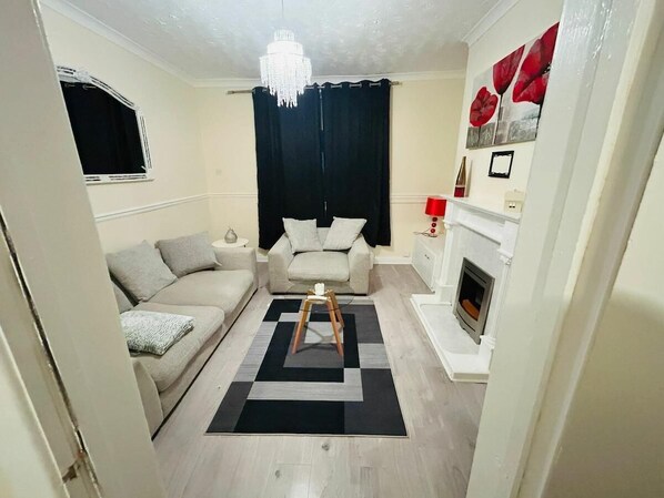 A living room with a sofa, a small table, a fireplace, and a chandelier.