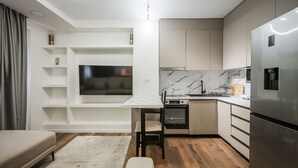 Una cucina moderna con elettrodomestici integrati, un'area pranzo e una TV a parete.