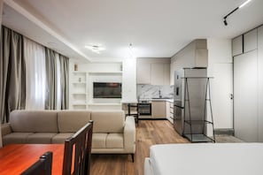 A modern hotel room with a sofa, a dining table, a kitchen area, and a bed. - City Vibes Studio Tirana Center (Tirana)