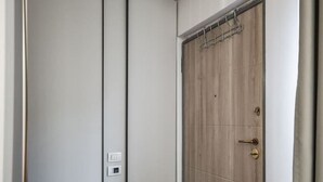 Una stanza con una porta scorrevole, una sedia nera e un pavimento in legno.