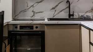Una cucina con forno a incasso, lavello e schienale in marmo.
